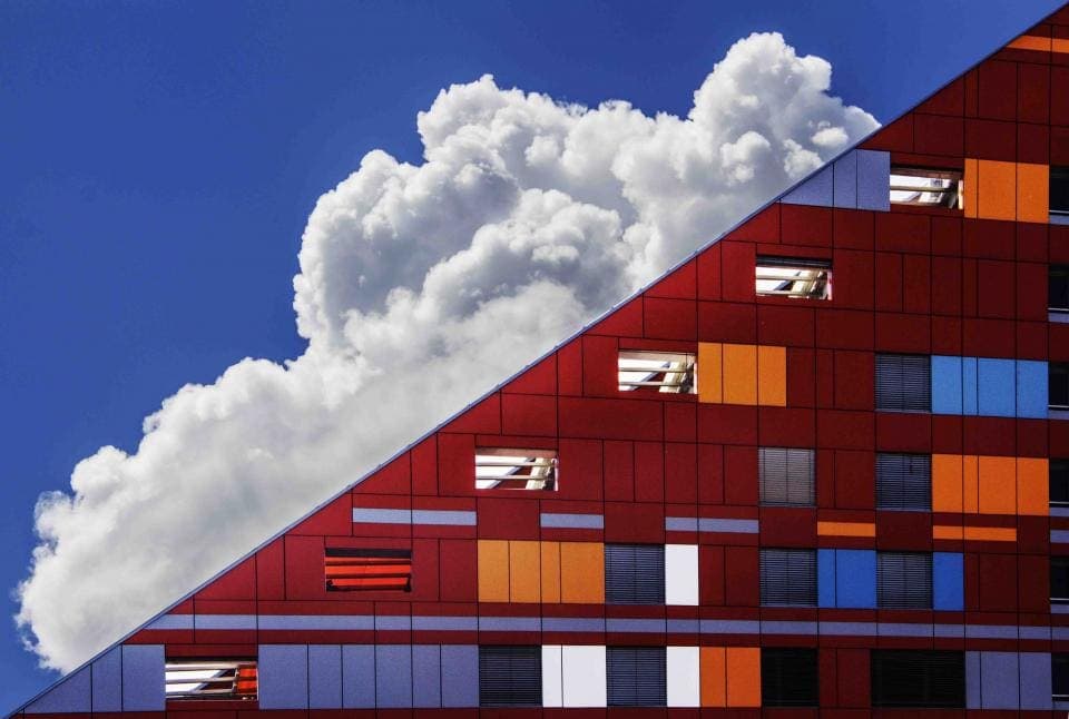 Red building facade against a blue sky with clouds