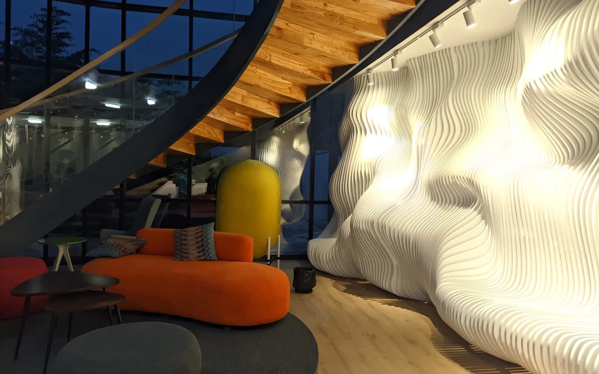 Designer interior with a sculpted wall, spiral stair and orange sofa